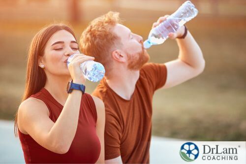 An image of a man and woman drinking water bottles